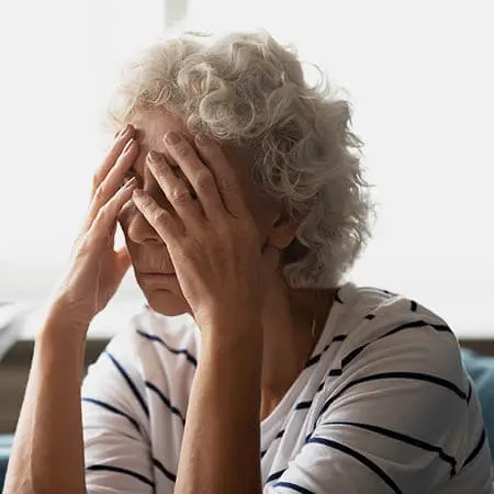 Image of a senior woman with her hands on her head looking frustrated