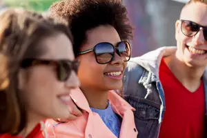 Three young people wearing sunglasses and smiling at the camera