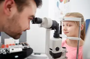 A girl is having her eyes examined by a doctor in an optical clinic
