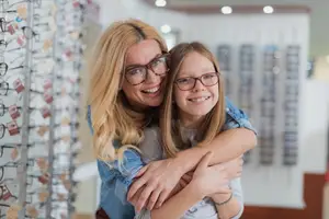 Mother and daughter in a glasses shop smiling at the camera