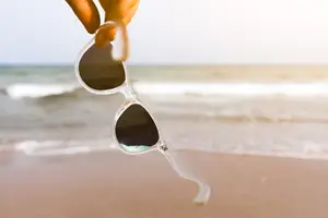 Person holding sunglasses on a beach