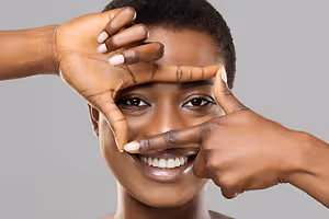 A smiling woman making a frame with her hands around her face