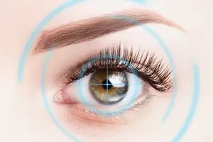 A close-up of a person's eye with brown iris and long eyelashes, framed by a blue circle, set against a pinkish background.