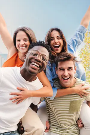 Four people smiling and laughing with arms around each other