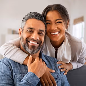 A smiling couple on a couch in a living room