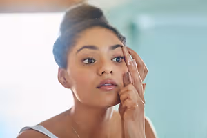 A woman is about to insert a contact lens into her eye