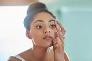 A woman is about to insert a contact lens into her eye
