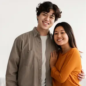 An adult man and woman are smiling and standing close to each other
