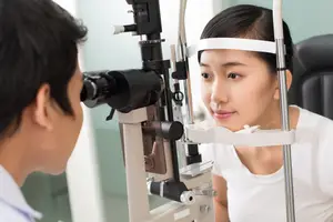 woman looking into an eye exam machine while a doctor looks through a lens