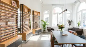 A photo of an optical shop with a desk, a sofa, a table, and glasses racks on the wall