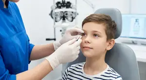 An optometrist examining a young boy's eye using a slit lamp