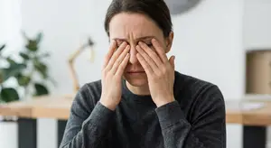 woman rubbing her temples while looking at the camera