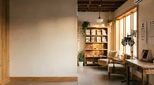 Interior of a room with a bookshelf, chairs, and a desk with a lamp and mirror, featuring a warm and inviting atmosphere.
