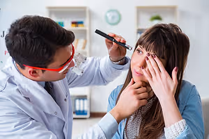 A doctor examines a patient's eyes with a medical instrument in a clinic.