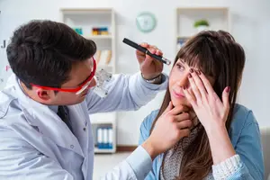 A doctor examines a patient's eyes with a medical instrument in a clinic.