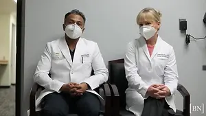 Dr. Deepan Salvedurai and Dr. Asura Salvedurai sitting in chairs wearing masks and lab coats