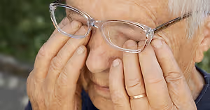 Senior woman with glasses touching her eyes with her hands