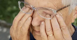 Senior woman with glasses touching her eyes with her hands