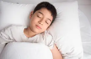 Boy sleeping on a pillow with his eyes closed