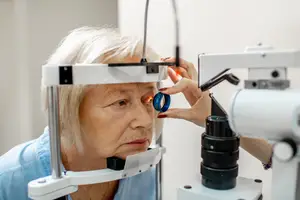 A woman is having her eyes checked by an optometrist using a phoropter