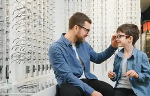 A man adjusting a young boys glasses in an optical shop