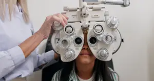 A woman is adjusting an eye-testing machine on a girl's head