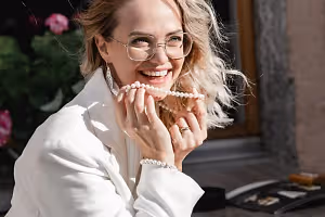 Blonde woman wearing white blazer and pearl necklace smiling at the camera
