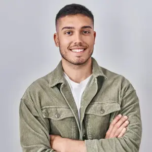 A man is smiling and posing for a photo with his arms crossed