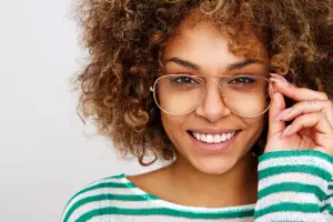 A smiling woman wearing glasses and a striped sweater is posing for a picture