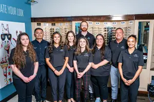 A group of people wearing black shirts standing in front of a wall with an image of sunglasses and frames
