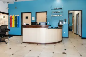 A blue-walled reception area with a desk, computer, and colorful pencil-like objects mounted on the wall