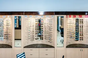 A showroom of Oakley sunglasses and other eyewear in an optical shop with a glass wall and mirrors for customers to try on glasses.
