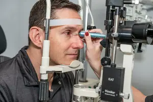A man is having an eye examination with an optometrist using an ophthalmoscope
