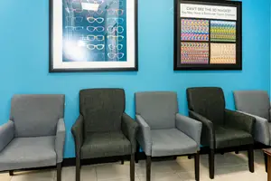 A room with gray chairs and blue walls with a picture of glasses and a sign about vision disorders