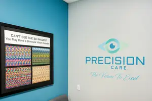 An eye care office wall with a framed poster and a logo for Precision Eye Care.