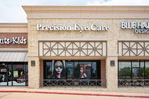 Front of Precision Eye Care, the College Station eye care center building with brick walls, glass windows, and metal railings.