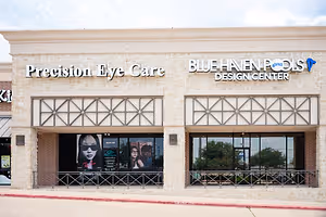 A storefront with two signs, one reading Precision Eye Care and the other Blue Haven Pools Design Center