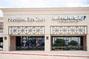 A storefront with two signs, one reading Precision Eye Care and the other Blue Haven Pools Design Center