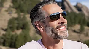 Man smiling while wearing sunglasses outdoors