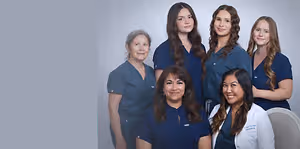 A group of women in blue uniforms are smiling and posing for a photograph.