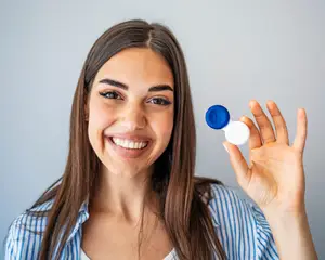 woman holding plastic container with contact lenses, indoors