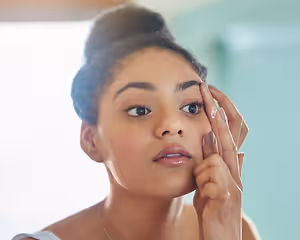 helping her live the life she envisions. shot of an attractive young woman putting in her contact lenses at home.