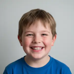 A smiling young boy with short hair and wearing a blue shirt