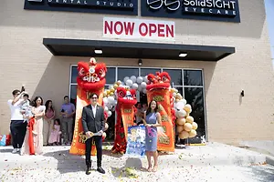 Grand opening celebration outside SolidSight Eye Care with lion dancers, balloons, and people gathered