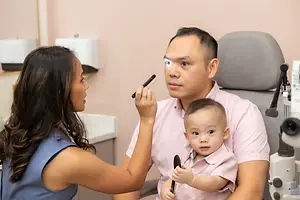 Eye care professional examining a father and child in an optometry office