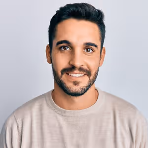 portrait of a smiling man with short hair and a beard wearing a beige sweater