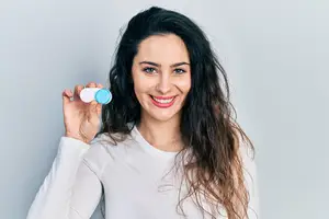 Woman holding a bottle of eye drops in front of her face