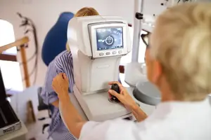 A person is getting an eye exam using a machine in an optometrist's office.