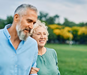 A senior couple walking together in a park during the daytime.