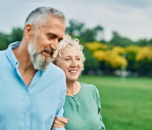 A senior couple walking together in a park during the daytime.